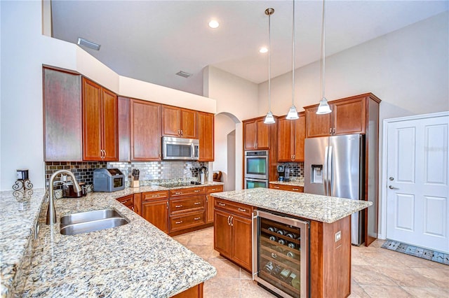 kitchen with visible vents, appliances with stainless steel finishes, arched walkways, beverage cooler, and a sink