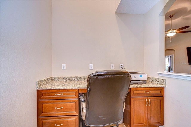 office space featuring built in desk, arched walkways, and ceiling fan
