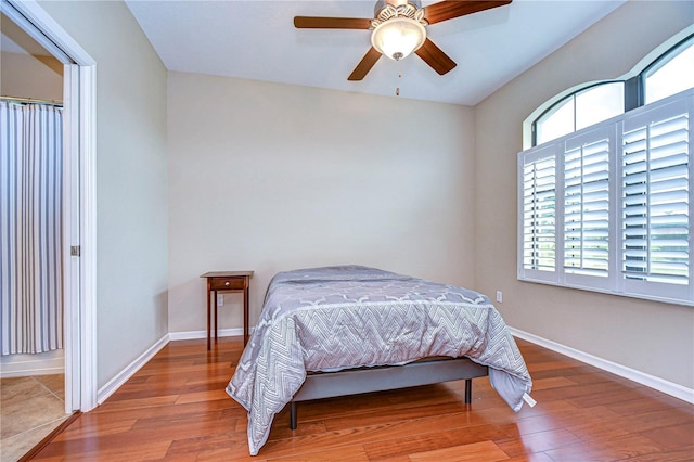 bedroom with ceiling fan, baseboards, and wood finished floors