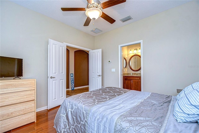 bedroom featuring baseboards, a ceiling fan, visible vents, arched walkways, and wood finished floors