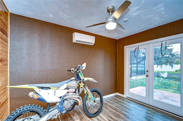 game room featuring baseboards, french doors, a wall unit AC, ceiling fan, and wood finished floors