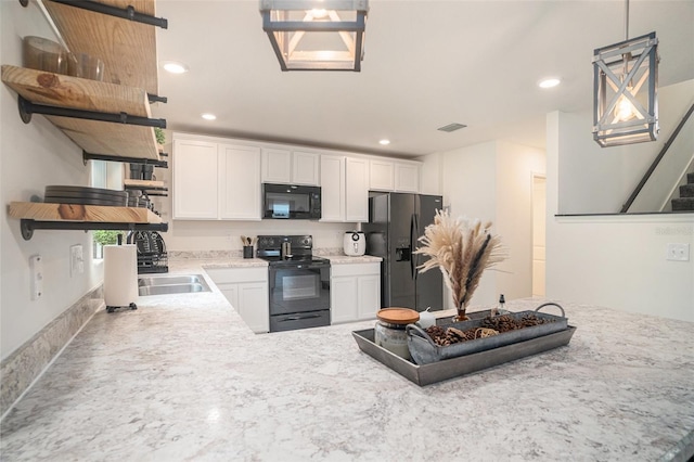 kitchen featuring pendant lighting, sink, white cabinetry, and black appliances