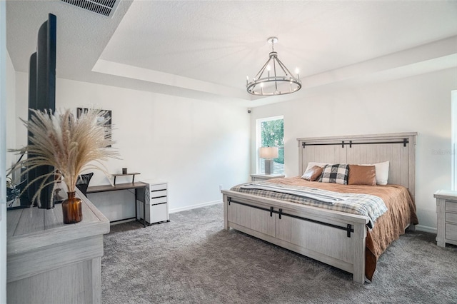 carpeted bedroom featuring a notable chandelier and a tray ceiling