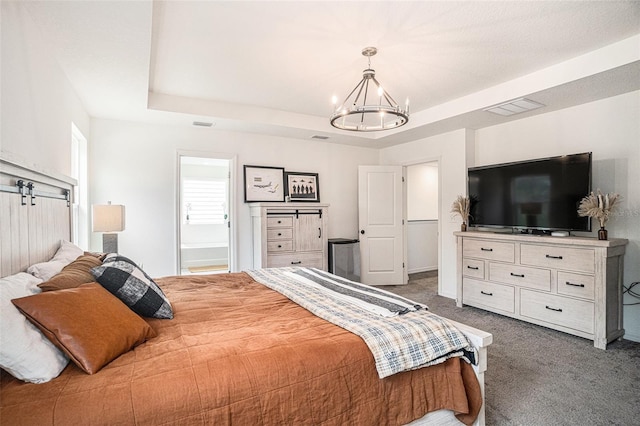 carpeted bedroom with an inviting chandelier, a tray ceiling, and ensuite bath