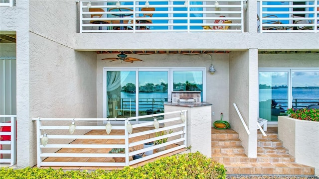 view of exterior entry with ceiling fan and a balcony