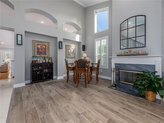 dining space with a high ceiling, ceiling fan, crown molding, and a premium fireplace