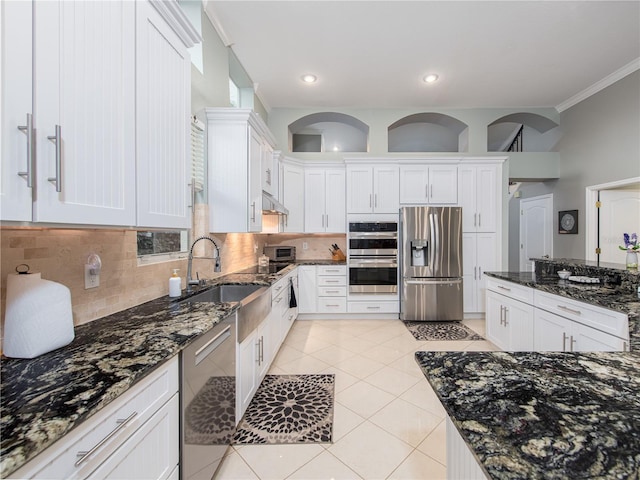 4709 Corsage Dr, Lutz, FL 33558 - kitchen with appliances with stainless steel finishes, white cabinetry, dark stone countertops, tasteful backsplash, and light tile patterned floors