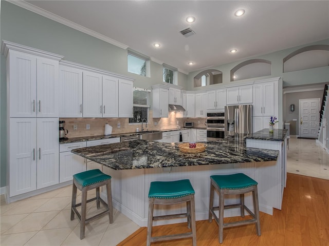 kitchen with white cabinetry, a breakfast bar, a spacious island, and appliances with stainless steel finishes