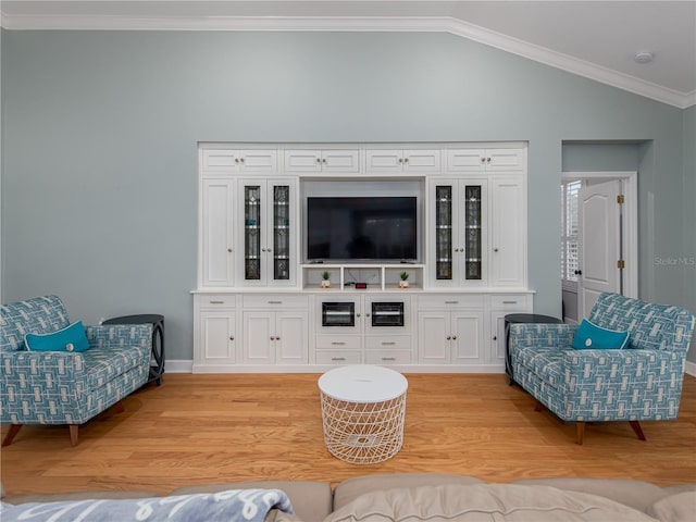 living room featuring light hardwood / wood-style floors, vaulted ceiling, and ornamental molding