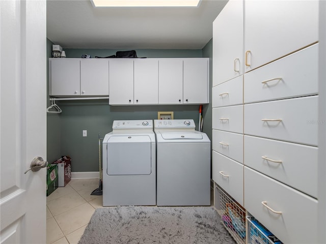 laundry room with washer and dryer, cabinets, and light tile patterned floors