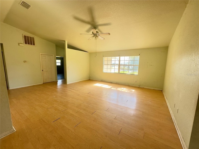 spare room featuring a textured ceiling, light hardwood / wood-style flooring, ceiling fan, and lofted ceiling