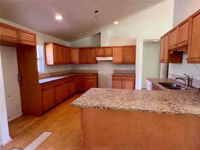 kitchen with kitchen peninsula, sink, light hardwood / wood-style floors, and vaulted ceiling