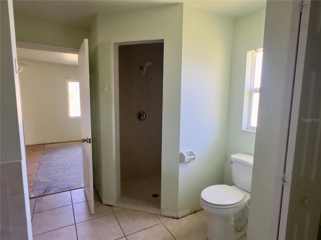 bathroom featuring tile patterned floors, plenty of natural light, toilet, and tiled shower