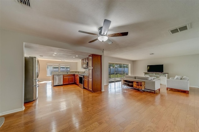 unfurnished living room featuring ceiling fan, light hardwood / wood-style flooring, and sink