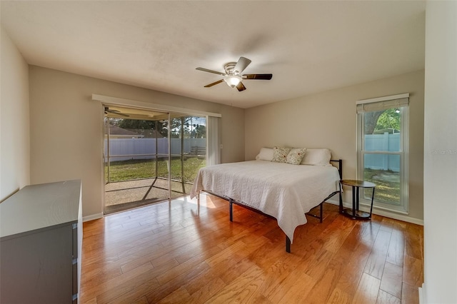 bedroom featuring access to outside, multiple windows, ceiling fan, and hardwood / wood-style floors