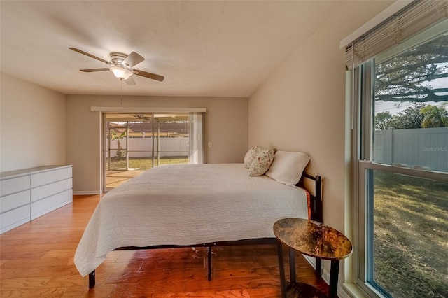 bedroom featuring ceiling fan, access to exterior, light hardwood / wood-style flooring, and multiple windows