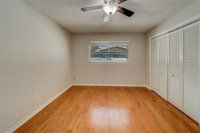 unfurnished bedroom featuring ceiling fan, a closet, and light hardwood / wood-style flooring