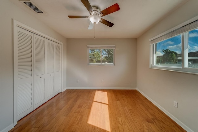 unfurnished bedroom with ceiling fan, light wood-type flooring, and a closet