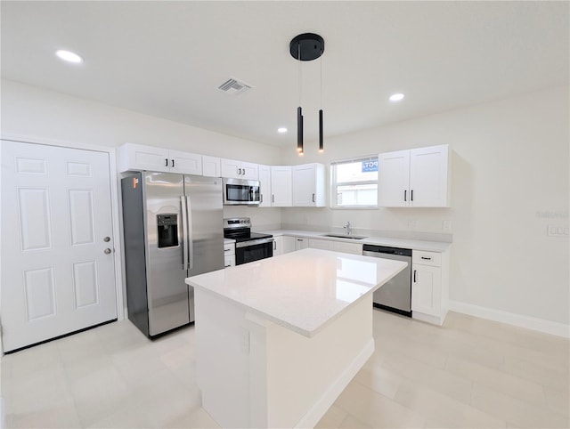 kitchen with sink, decorative light fixtures, appliances with stainless steel finishes, a kitchen island, and white cabinets