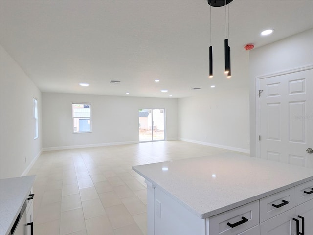 kitchen featuring a center island, white cabinets, light stone counters, and decorative light fixtures