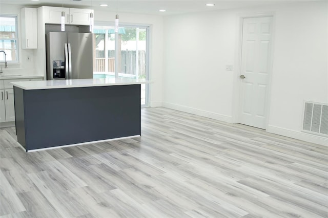 kitchen with white cabinetry, sink, a center island, stainless steel refrigerator with ice dispenser, and decorative light fixtures