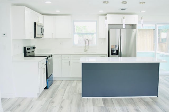 kitchen featuring pendant lighting, white cabinets, sink, light hardwood / wood-style flooring, and stainless steel appliances