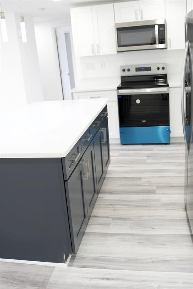 kitchen featuring white cabinets, pendant lighting, and appliances with stainless steel finishes