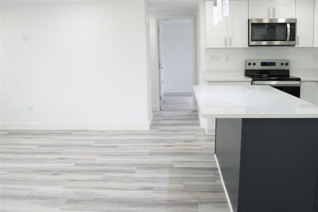 kitchen with white cabinetry, light hardwood / wood-style flooring, a kitchen island, and stainless steel appliances