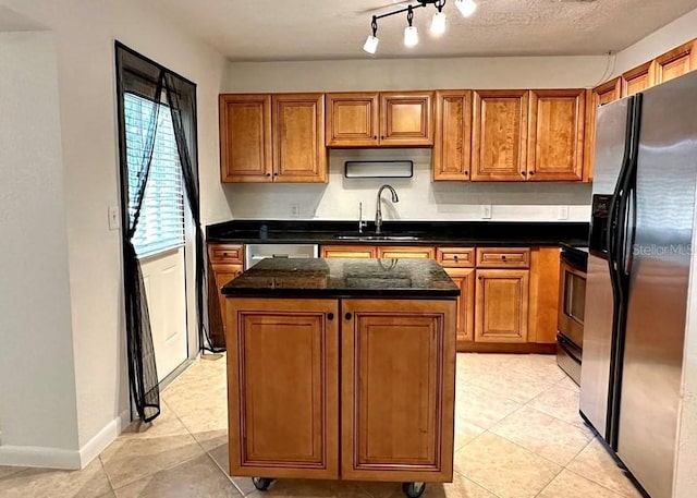 kitchen featuring sink, dark stone countertops, a textured ceiling, a kitchen island, and stainless steel appliances