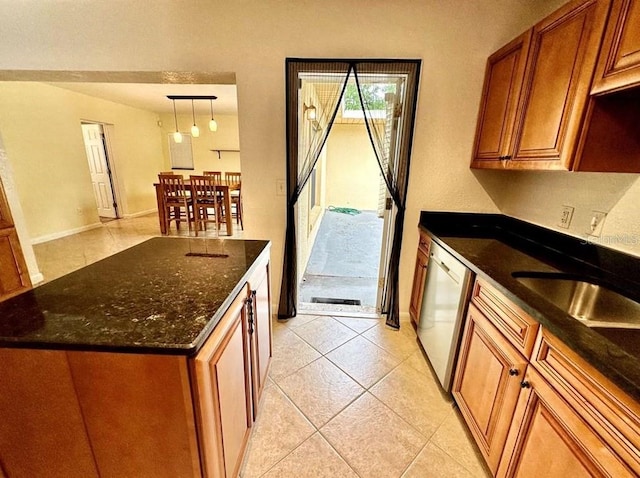 kitchen with dark stone counters, dishwasher, light tile patterned floors, and hanging light fixtures