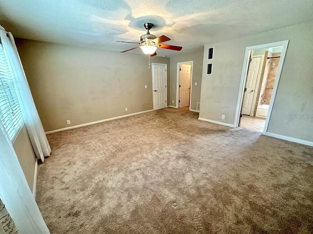 unfurnished bedroom featuring ceiling fan, ensuite bathroom, a textured ceiling, and light carpet