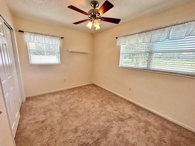 spare room with ceiling fan and light carpet