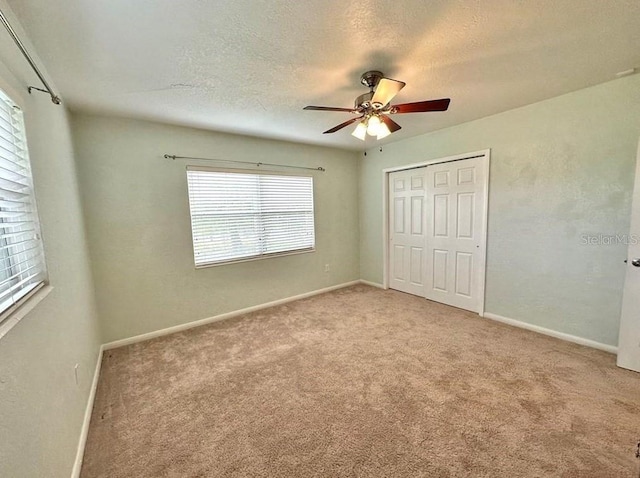 unfurnished bedroom featuring a textured ceiling, ceiling fan, light carpet, and a closet