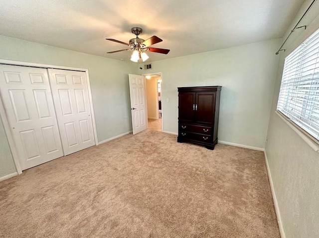 unfurnished bedroom featuring ceiling fan, a closet, and light colored carpet