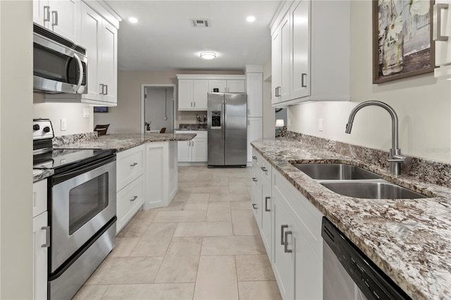 kitchen featuring light stone countertops, stainless steel appliances, white cabinetry, and sink