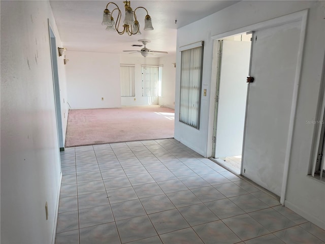 spare room featuring light carpet and ceiling fan with notable chandelier