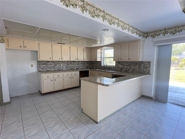 kitchen with sink, light tile patterned floors, cream cabinetry, and kitchen peninsula