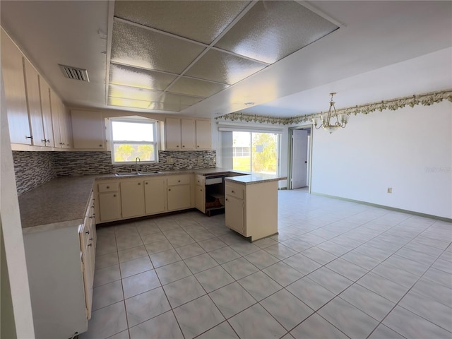 kitchen featuring kitchen peninsula, decorative light fixtures, cream cabinetry, light tile patterned flooring, and sink