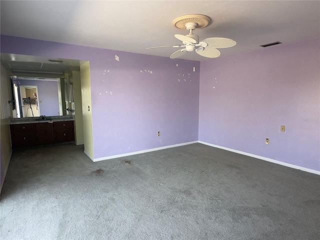 empty room featuring ceiling fan and dark carpet