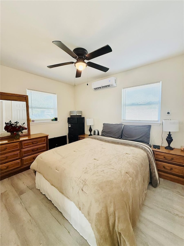 bedroom with a wall mounted AC, ceiling fan, and light wood-type flooring