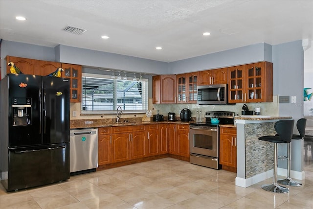 kitchen featuring dark stone countertops, decorative backsplash, sink, and stainless steel appliances