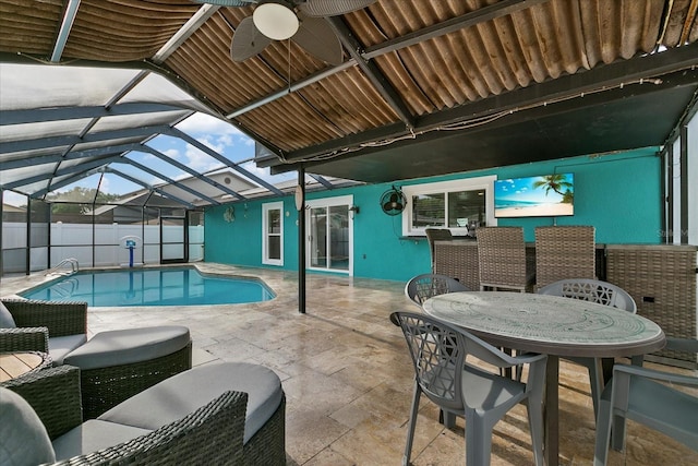 view of pool with glass enclosure, ceiling fan, and a patio