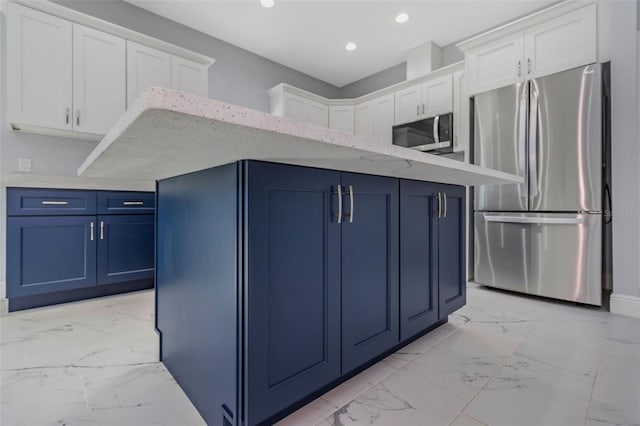 kitchen featuring appliances with stainless steel finishes, white cabinetry, a center island, light stone counters, and blue cabinetry