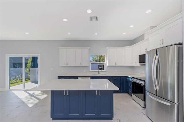 kitchen with appliances with stainless steel finishes, blue cabinets, white cabinetry, sink, and a center island