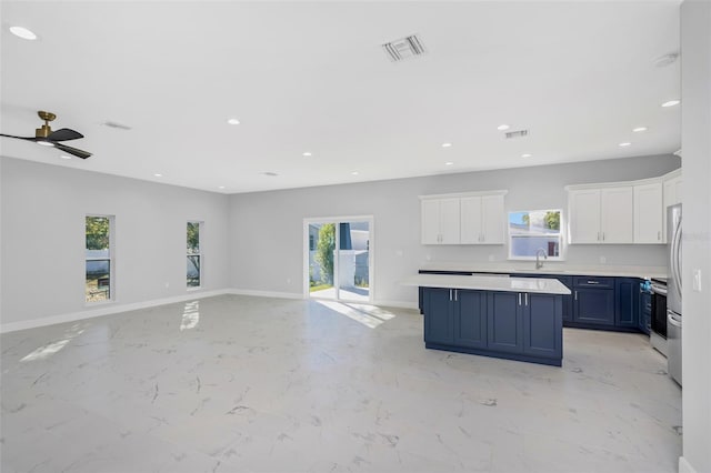 kitchen with white cabinetry, sink, blue cabinetry, and a healthy amount of sunlight