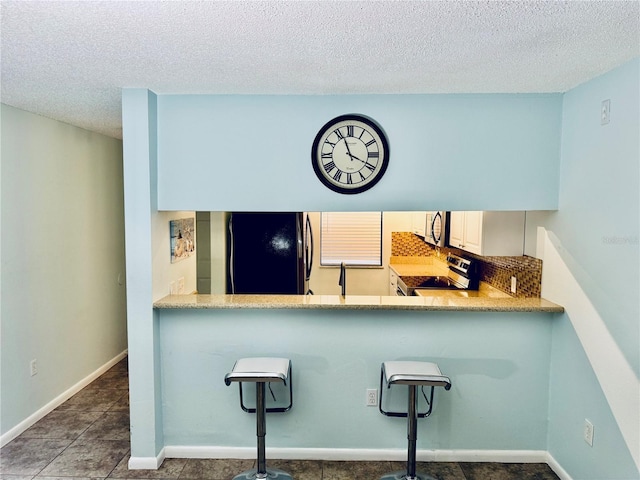 kitchen with appliances with stainless steel finishes, kitchen peninsula, a textured ceiling, and white cabinets