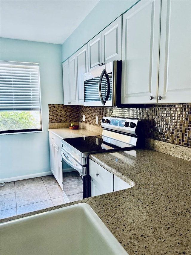 kitchen featuring white cabinetry, appliances with stainless steel finishes, light tile patterned floors, and backsplash