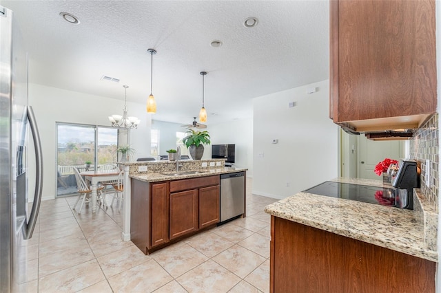 kitchen featuring light stone countertops, stainless steel appliances, sink, a chandelier, and hanging light fixtures