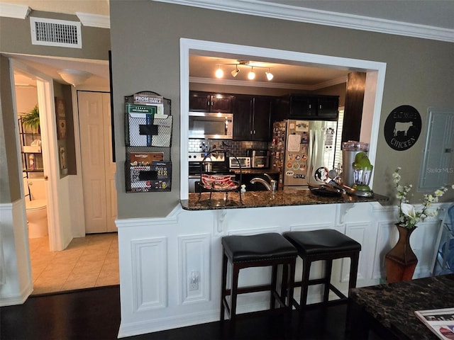 kitchen with ornamental molding, stainless steel appliances, kitchen peninsula, and a kitchen bar