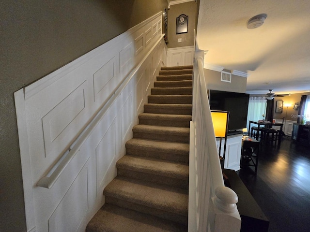 stairs with hardwood / wood-style flooring, ornamental molding, and ceiling fan